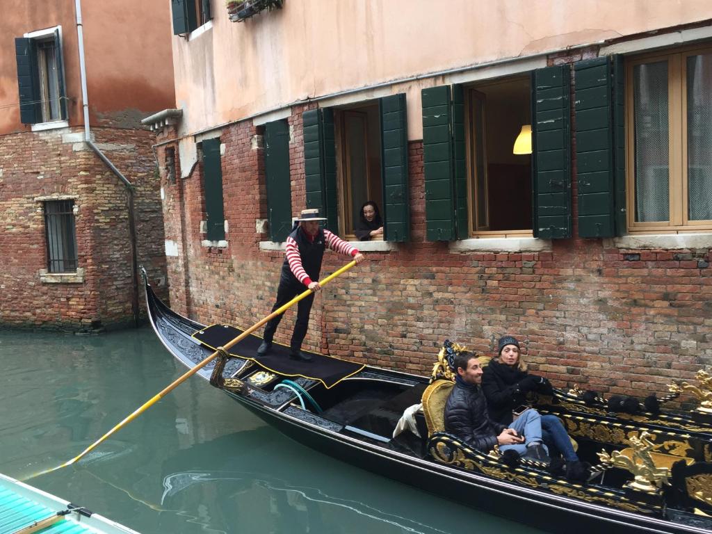 Um homem está de pé numa gôndola na água. em b&b allo squero em Veneza