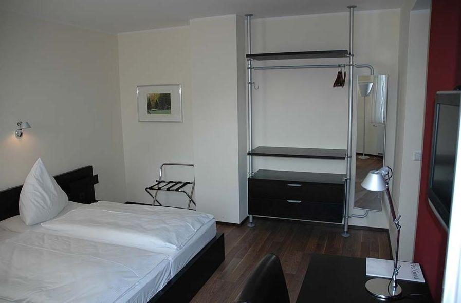 Schlafzimmer mit einem Bett und einem Schreibtisch mit einem Tisch in der Unterkunft Von Korff´S Rest & Relax Hotel in Meschede