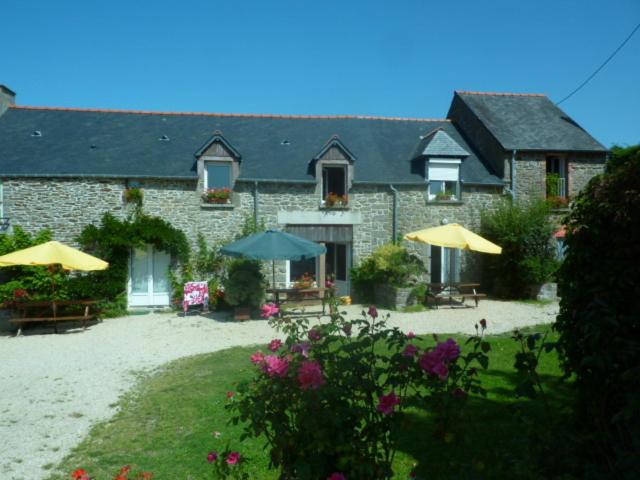 a brick house with umbrellas and chairs and tables at Gite Les Oyats in Cancale