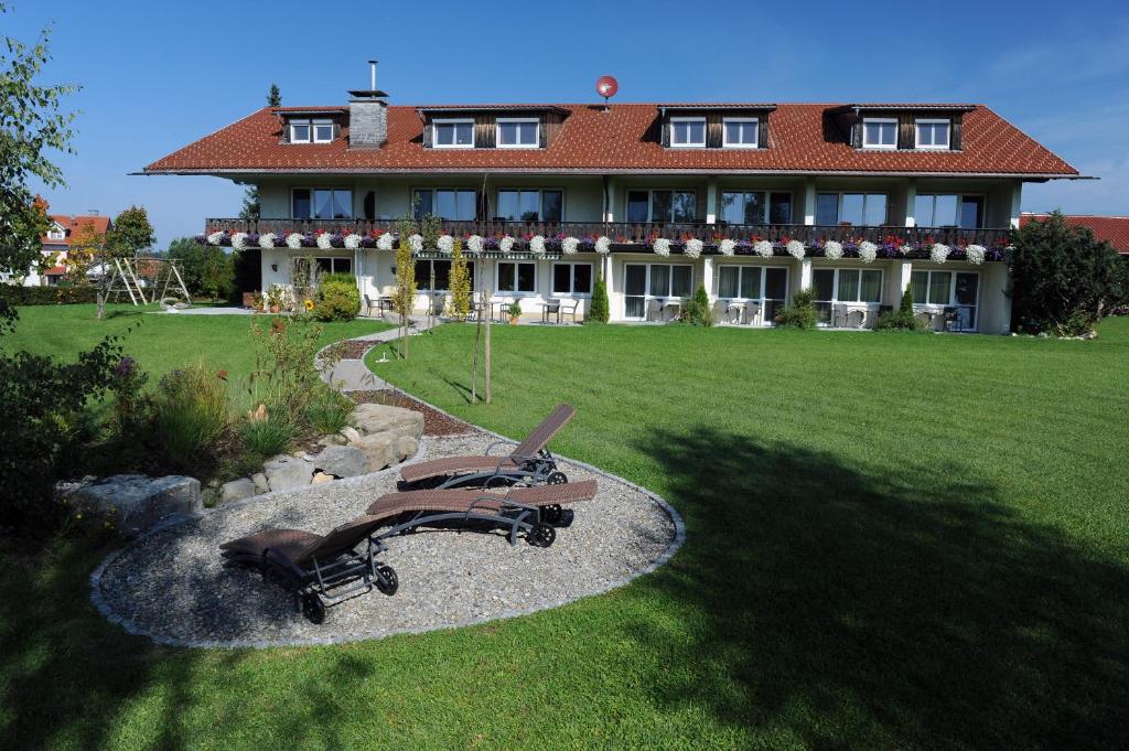 ein großes Haus mit einem großen Garten mit Stühlen davor in der Unterkunft Hotel Bergblick in Scheidegg