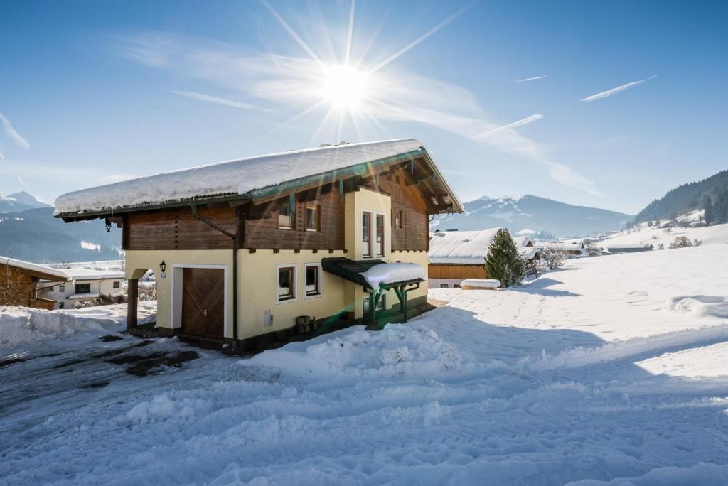 een huis bedekt met sneeuw met de zon erachter bij Ferienhaus Hubertus - PRECHTLHOF in Flachau