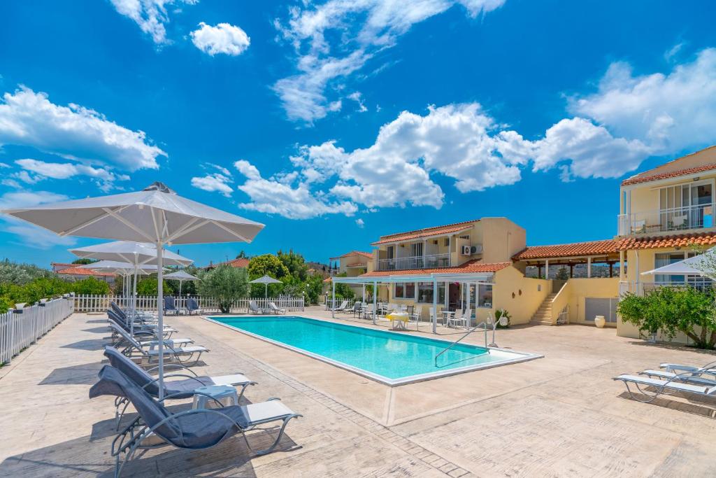 einem Pool mit Stühlen und Sonnenschirmen vor einem Gebäude in der Unterkunft Leonidas Resort in Ermioni