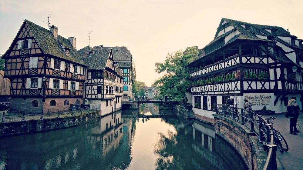 a group of buildings next to a river in a city at Le Vicus in Eckbolsheim