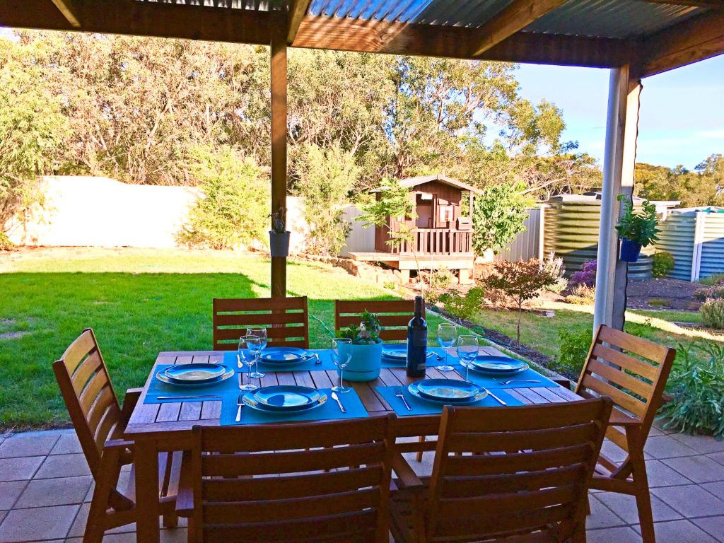 a wooden table with blue plates and chairs on a patio at Island Daydreamer in Kingscote