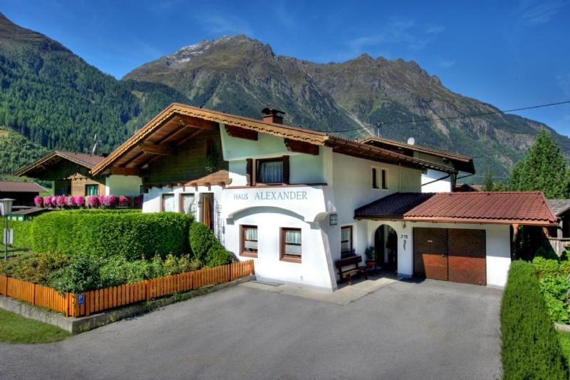 a white house with mountains in the background at Haus Alexander in Längenfeld