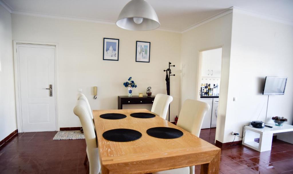 a dining room with a wooden table and white chairs at Alveiros Apartamentos Praia dos Aveiros in Albufeira