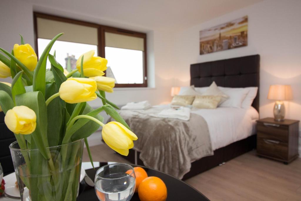 1 dormitorio con 1 cama y un jarrón con flores amarillas en Trafalgar House en Stoke on Trent