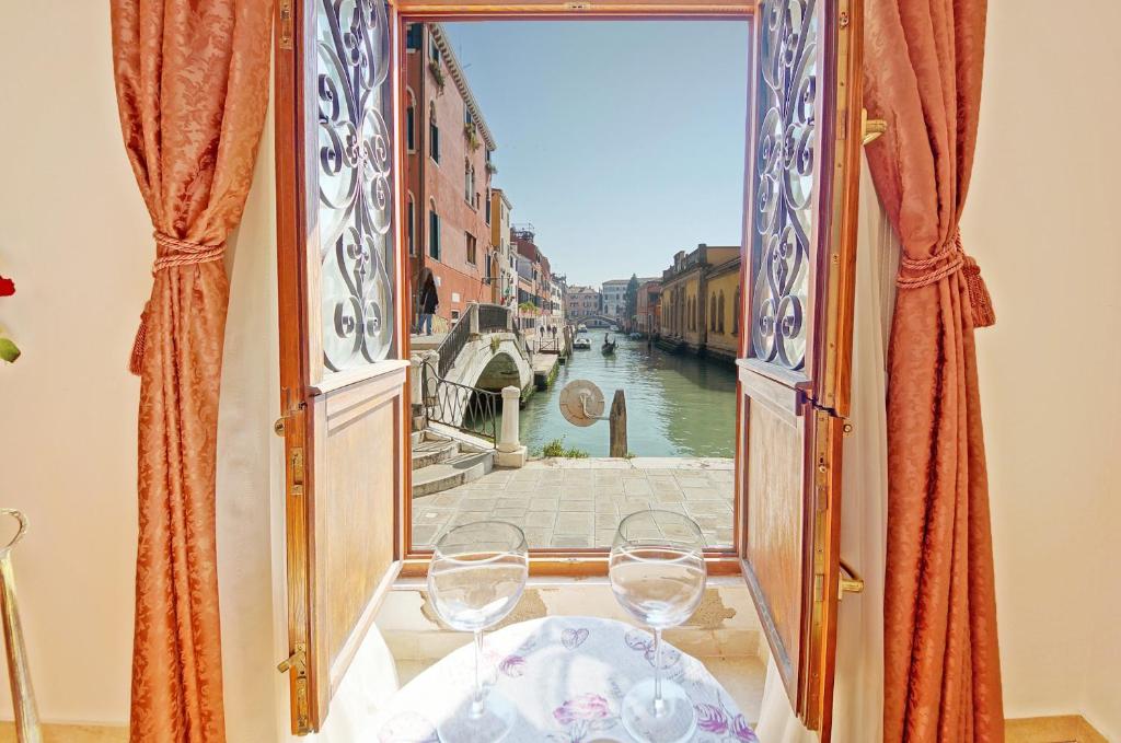 ヴェネツィアにあるDolceVita Apartments N 315のワイングラスをテーブルに置いた開口窓