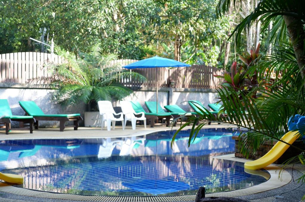 a pool with chairs and a slide in a yard at Khaolak Grand City in Khao Lak