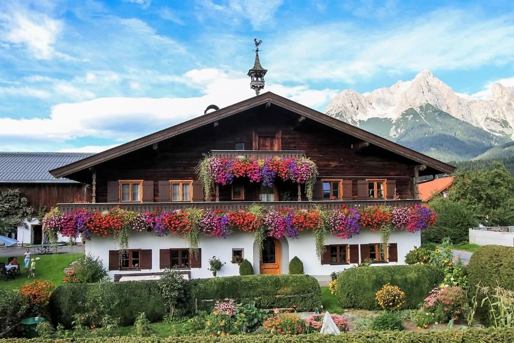 una casa con flores a un lado. en Mosshamhof, en Saalfelden am Steinernen Meer