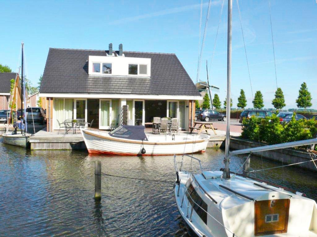 een boot aangemeerd bij een huis aan het water bij Holiday Home De Meerparel-7 in Uitgeest