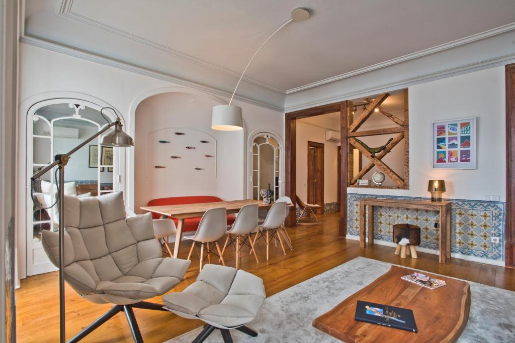 ein Wohnzimmer mit einem Tisch, Stühlen und einem Kamin in der Unterkunft Libest Chiado 4 - Alecrim in Lissabon