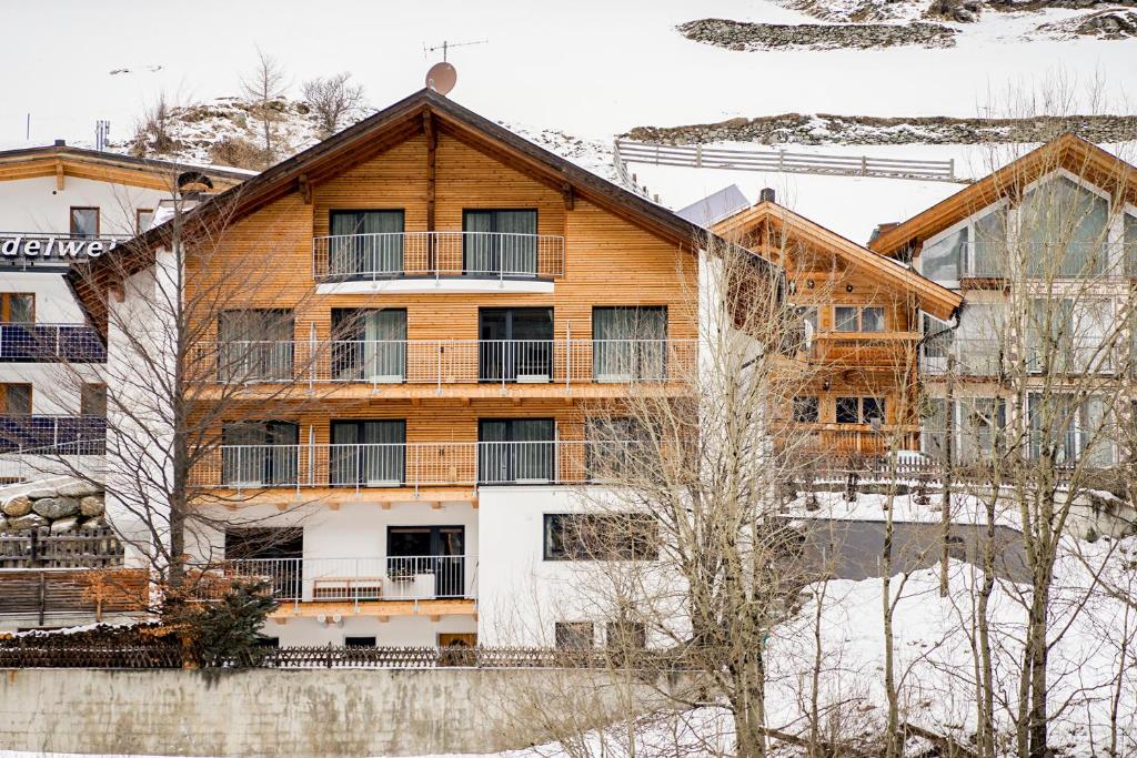 a wooden house with a balcony in the snow at Brandhof Lodge in Ischgl