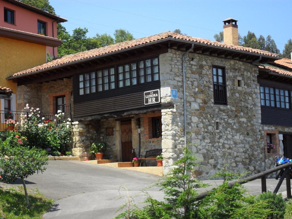 un edificio de piedra con un cartel delante en Hotel La Llosona, en Ribadesella