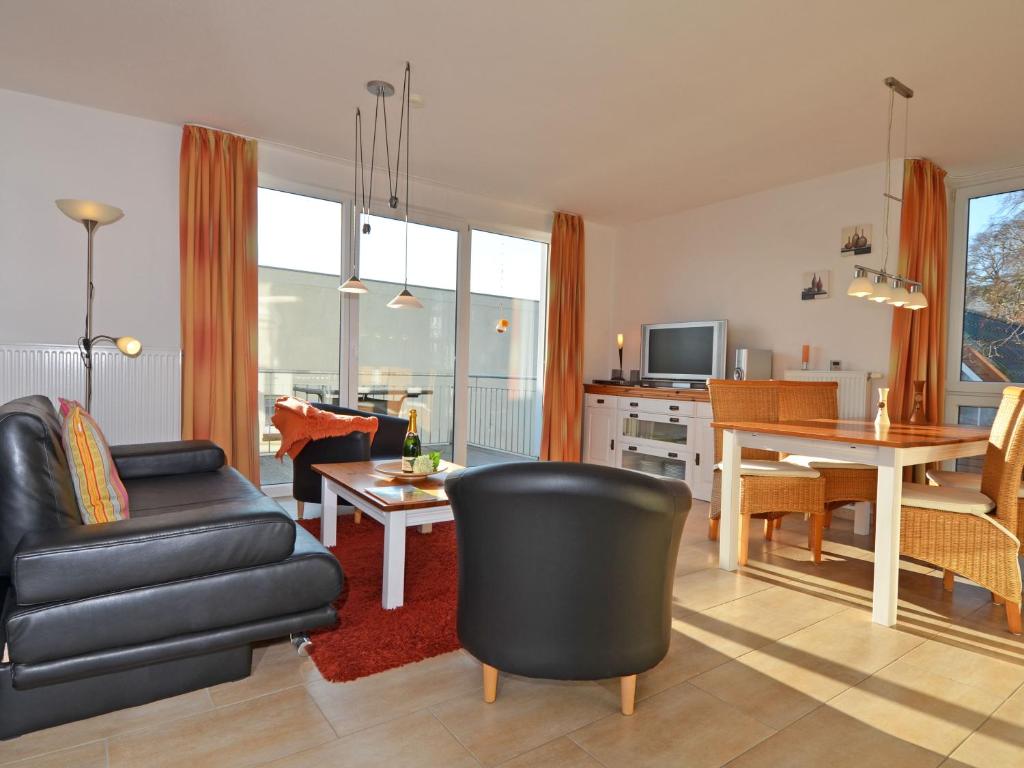ein Wohnzimmer mit einem schwarzen Ledersofa und einem Tisch in der Unterkunft Haus Möwe - Apt. 07 in Ostseebad Sellin