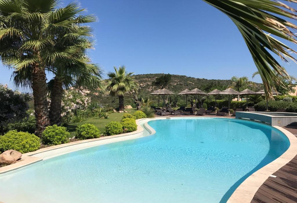 a swimming pool in a resort with palm trees at Résidence de Tourisme Mare e Macchia in Tizzano