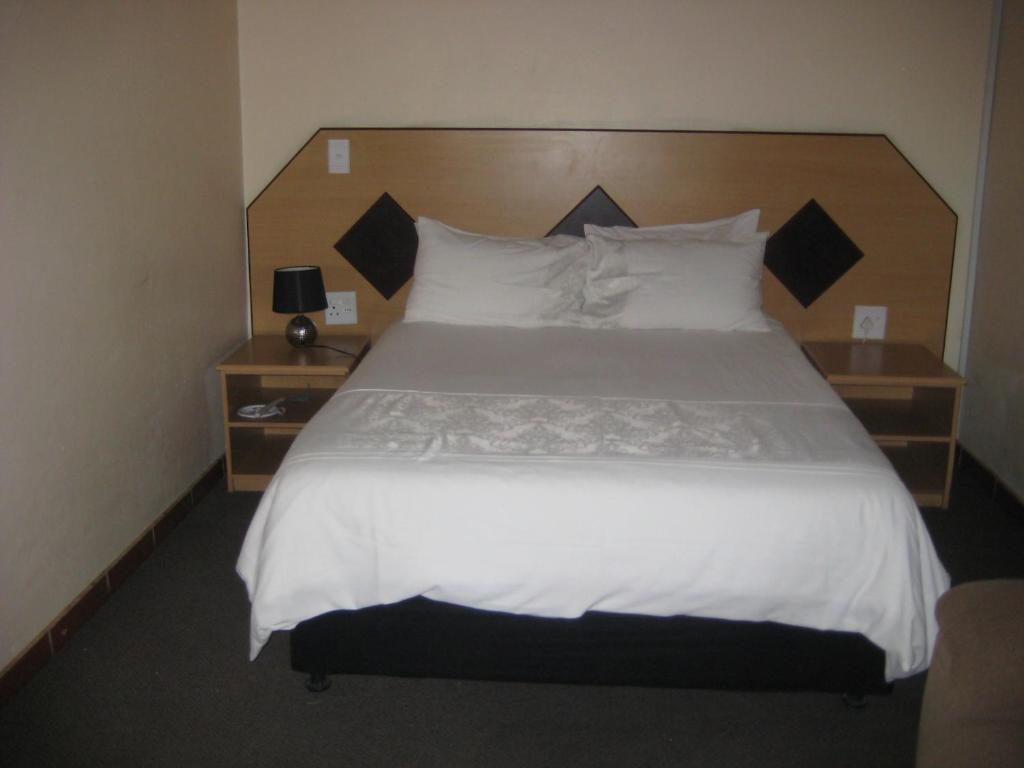 a bedroom with a large bed with white sheets and pillows at Black Swan Guesthouse in Maseru