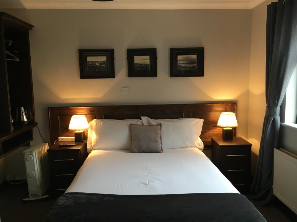 um quarto com uma cama grande e 2 candeeiros em The Midway Bar & Guesthouse em Dungloe