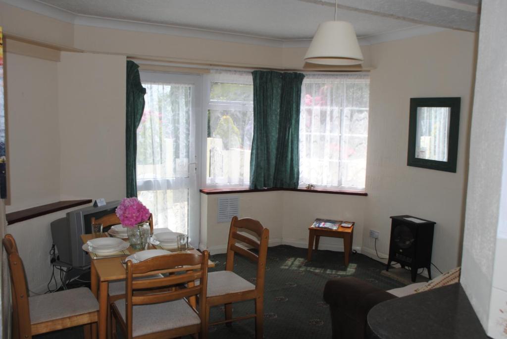 a living room with a table and chairs and windows at Ashbury Tor in Torquay
