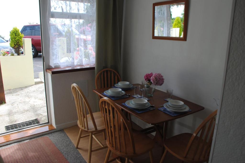 een eettafel en stoelen met een tafel en een raam bij Huccaby Tor Apartmernt in Torquay
