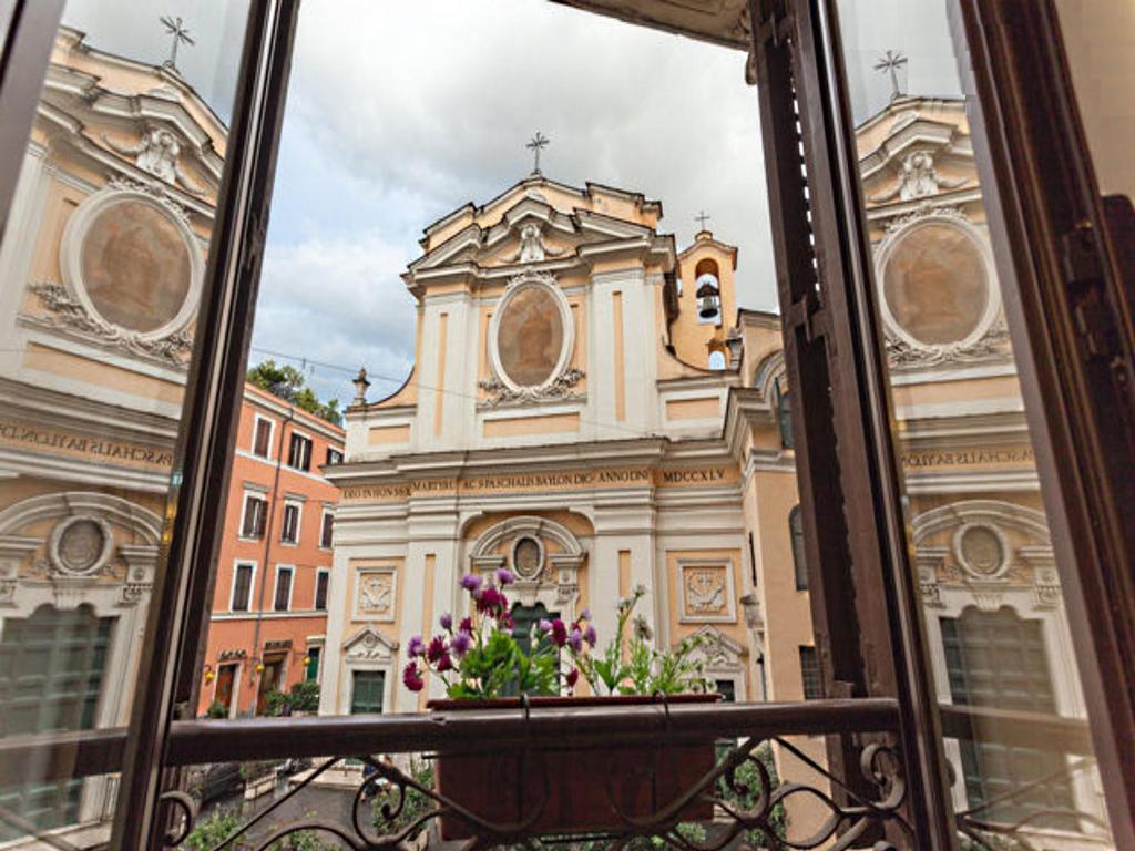 ein Fenster mit Blick auf ein Gebäude mit einer Kirche in der Unterkunft Magenta Collection Manara 4 in Rom