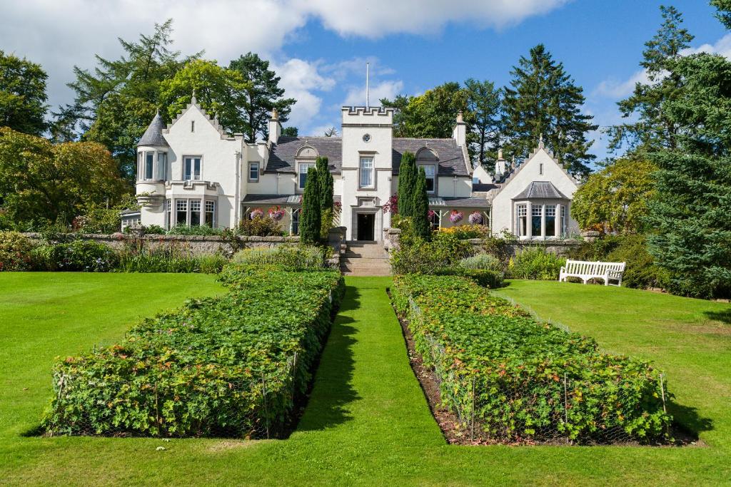 a large white house with a garden in front of it at Douneside House in Tarland