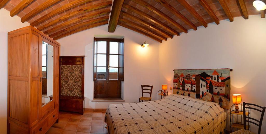 a bedroom with a large bed and a wooden ceiling at Villa esclusiva in Toscana con piscina privata in Montecastelli