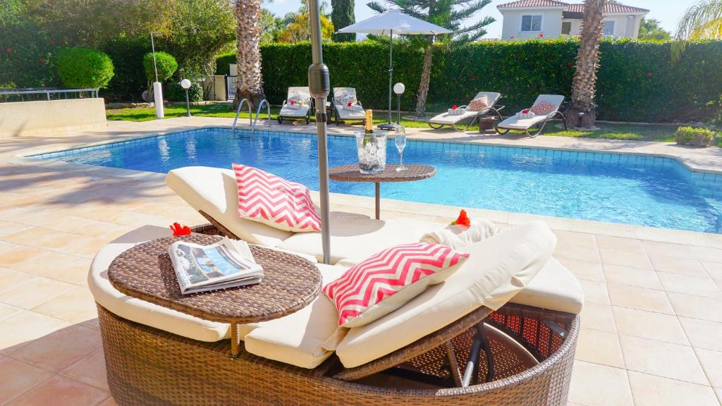 uma mesa de vime e cadeiras ao lado de uma piscina em Villa Casa Mia by Ezoria Villas em Coral Bay