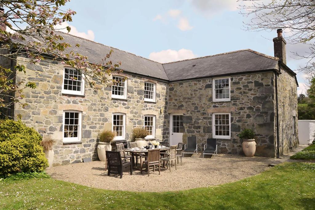 uma antiga casa de pedra com uma mesa e cadeiras em Bonython Farmhouse em Cury