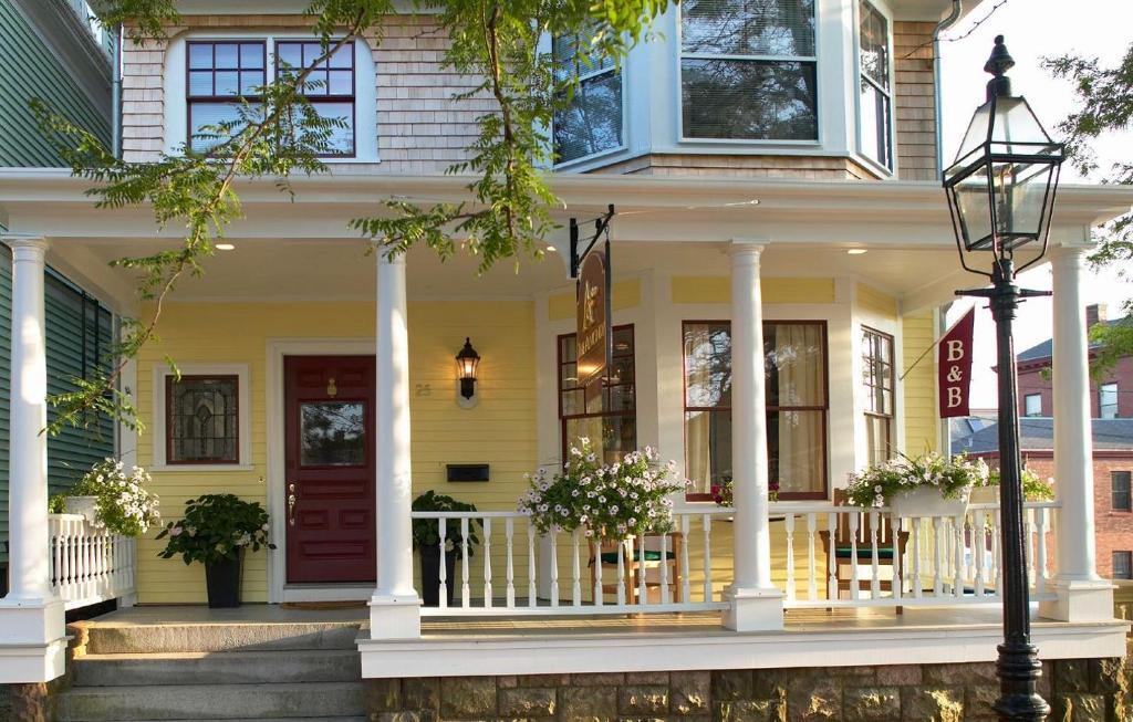 紐波特的住宿－Almondy Inn Bed & Breakfast，黄色的房子,设有门廊和红色的门