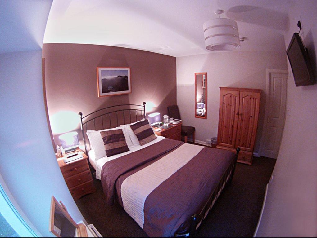 a bedroom with a large bed and a desk at Glyn Peris Guest House in Llanberis