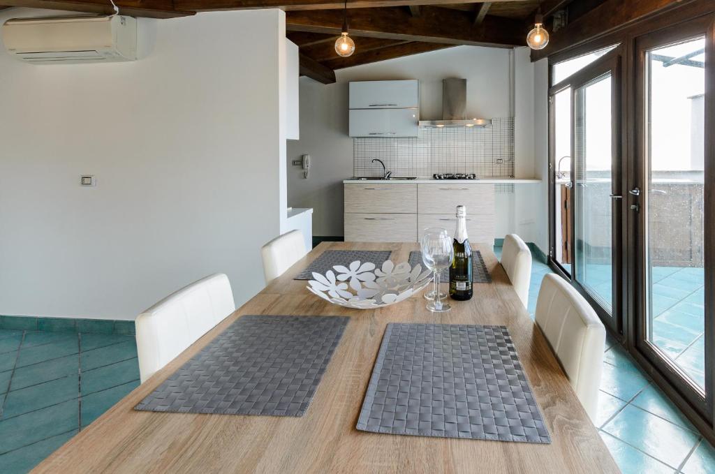 Sweet Taormina Apartment في تاورمينا: مطبخ مع طاولة خشبية مع كؤوس للنبيذ عليه