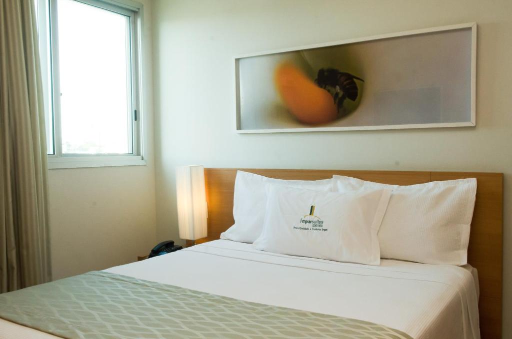 uma cama num quarto de hotel com uma fotografia na parede em Ímpar Suítes Cidade Nova em Belo Horizonte