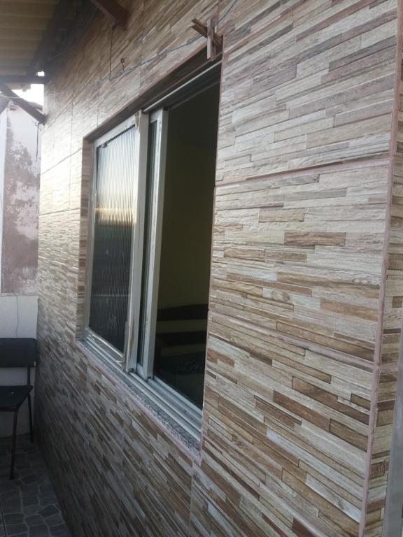 pared de ladrillo con ventana en una habitación en Duplex com dois Quartos, en Salvador