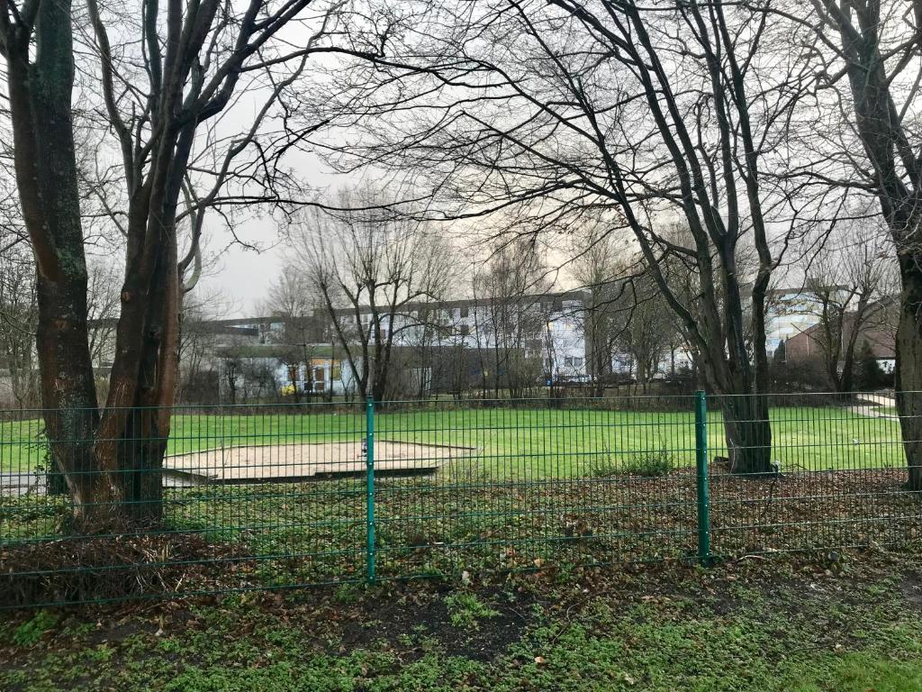 a chain link fence in a park with trees at Messewohnung Dormagen in Dormagen