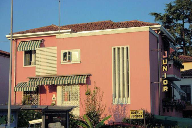 un edificio rosa con un cartello davanti di Albergo Junior a Padova