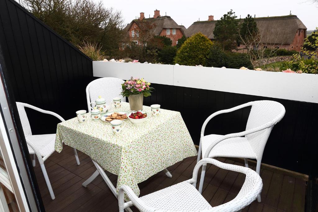 a table and chairs on a balcony with a table and flowers at Ferienwohnung Biberhüs OG in Archsum