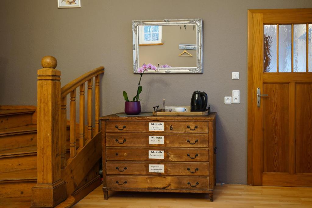 - une commode dans une pièce avec un escalier et un miroir dans l'établissement Pension Elise, à Wolkramshausen