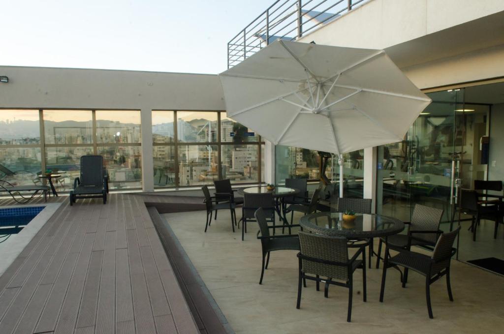 a patio with a table and chairs and an umbrella at Hotel Beaga Convention Expominas by MHB in Belo Horizonte