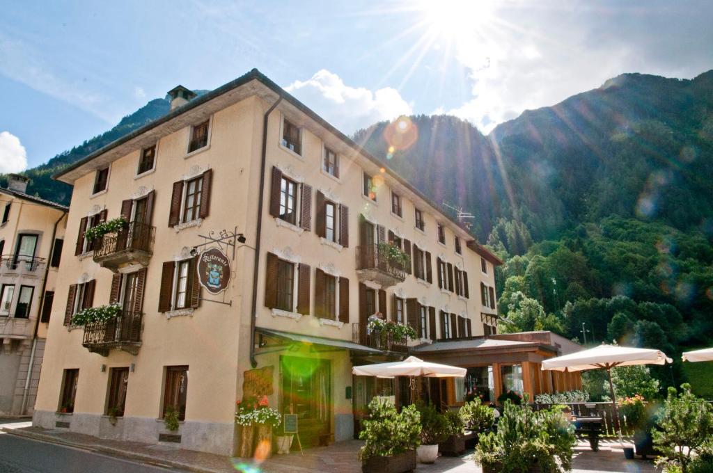 a building with umbrellas in front of a mountain at Hotel Pedretti in Branzi