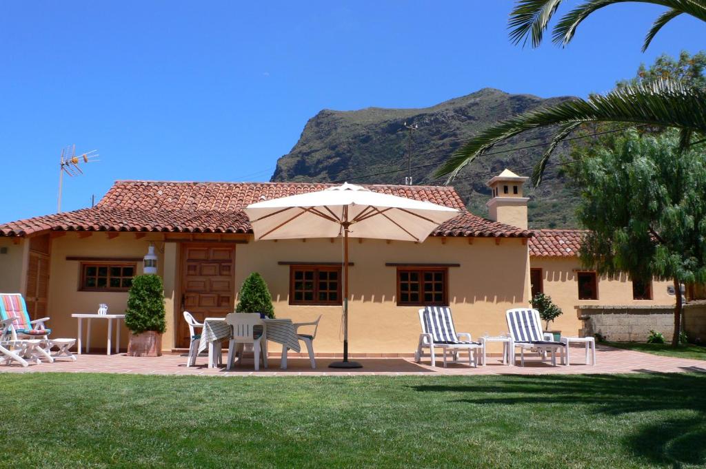 eine Terrasse mit Stühlen und einem Sonnenschirm vor einem Haus in der Unterkunft Casa"La Gomera" in Los Silos