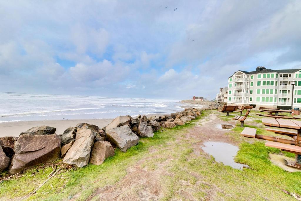a beach with rocks and a building and the ocean at Getaway Oceanfront Lodging in Rockaway Beach
