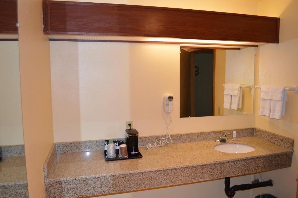 a bathroom counter with a sink and a mirror at Western Motel in Junction City