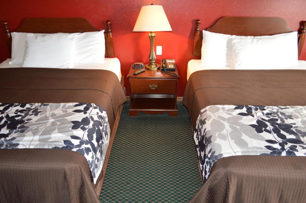 a hotel room with two beds and a table with a lamp at Western Motel in Junction City