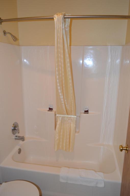 a white bath tub with a shower curtain in a bathroom at Western Motel in Junction City