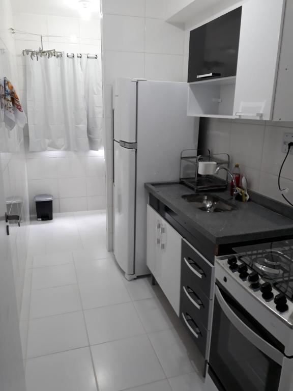 uma cozinha branca com um fogão e um frigorífico em Residencial Martinica I em Caraguatatuba