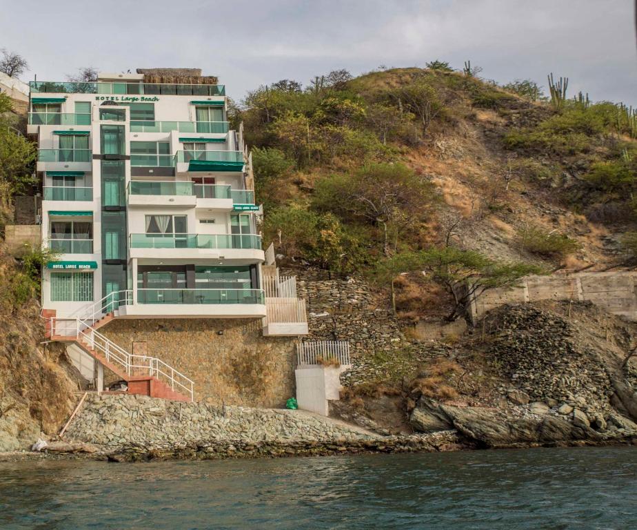 a large building on a hill next to the water at Hotel Large Beach in Taganga