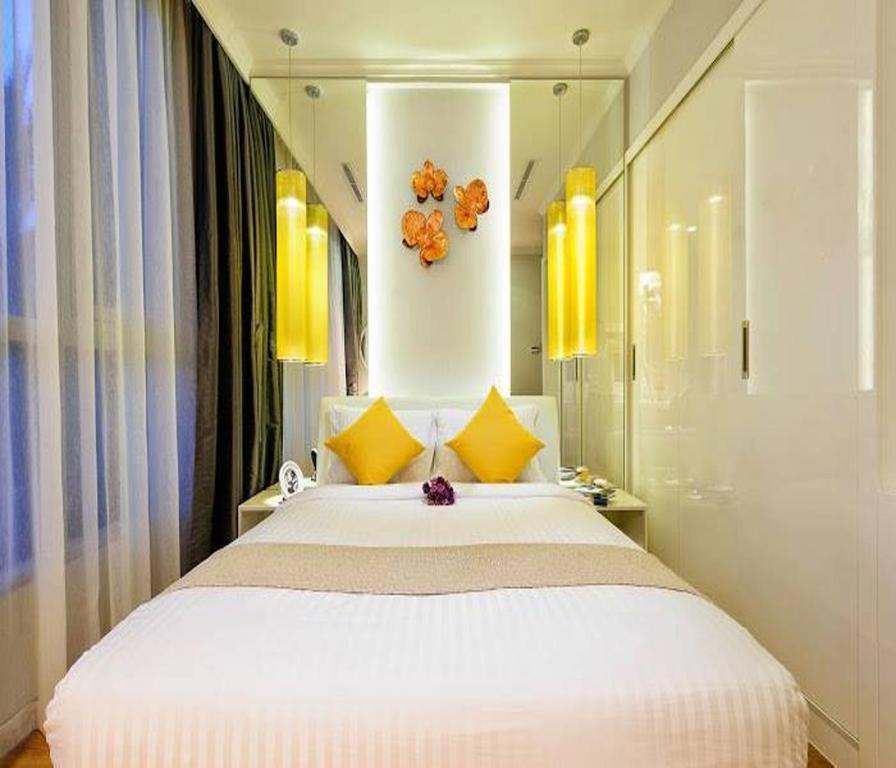 Un dormitorio con una gran cama blanca con toques amarillos en Vinhomes Central Park 2 Capitalland, en Ho Chi Minh