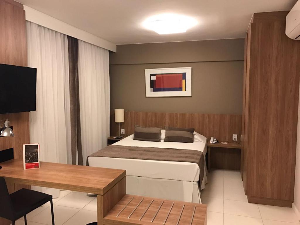 a hotel room with a bed and a desk at Rio Stay Rio Centro in Rio de Janeiro