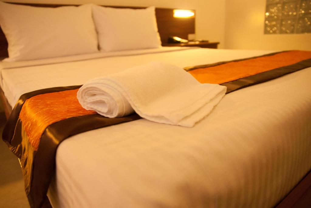 a hotel room with a bed with a towel on it at M Suites Hotel in Manila